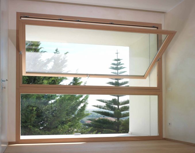Vista frontale di una finestra a bilico in legno con finitura naturale