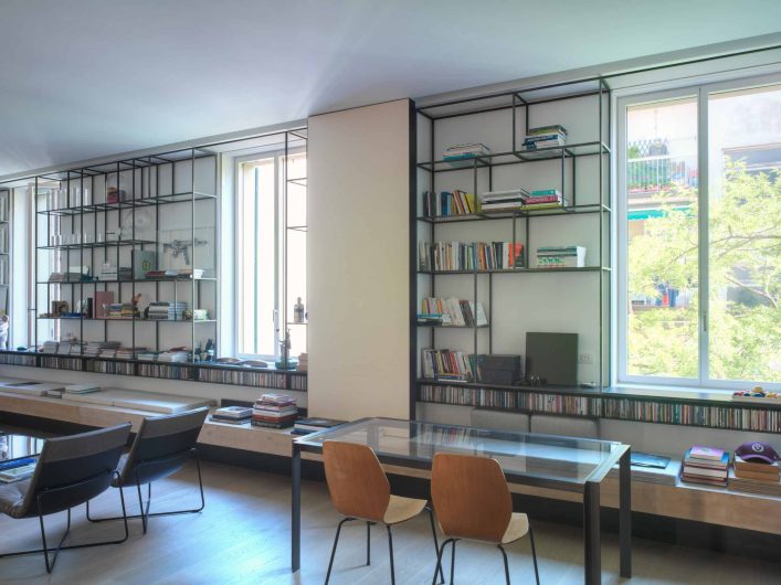 Vista della parete a libreria su misura dello studio d'arte Firenze, con tre finestre Skyline laccate bianche